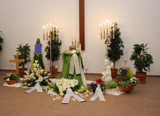 Urne mit grünem Tuch und weißem Blumenschmuck in der Trauerhalle