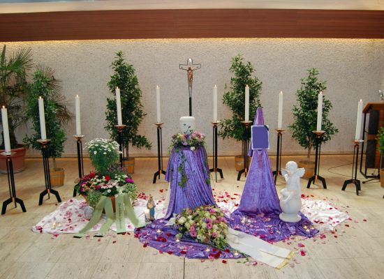 Urne auf violettem Tuch mit Blumenschmuck und Rosenblättern